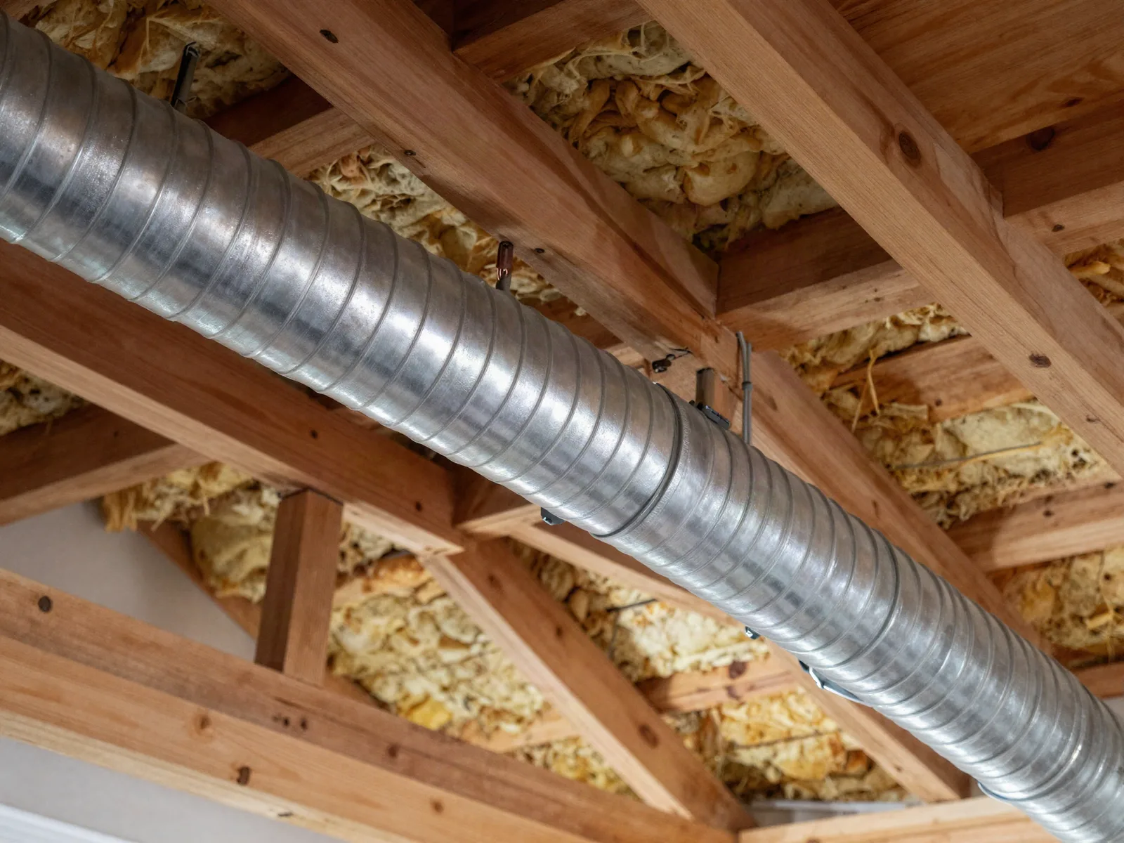 Residential duct system in a ceiling cavity showing the main trunk, branch runs and a ceiling register
